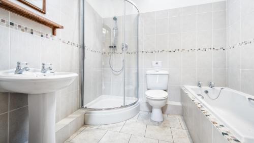 a bathroom with a toilet and a sink and a shower at The Old Milking Parlour in Barmston