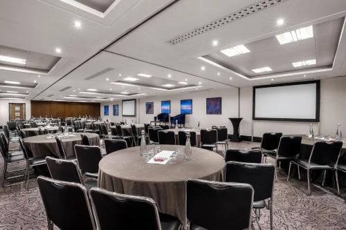 a conference room with tables and chairs and a screen at Leonardo Royal London St Paul’s in London