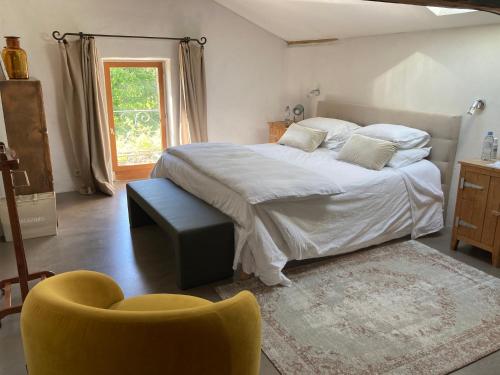 a bedroom with a large bed and a yellow chair at L'Angélus in Genay