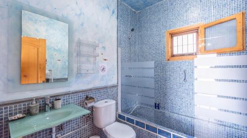 La salle de bains est pourvue de carrelage bleu, de toilettes et d'un lavabo. dans l'établissement Cortijo La Tata Almayate Alto by Ruralidays, à Almayate Alto