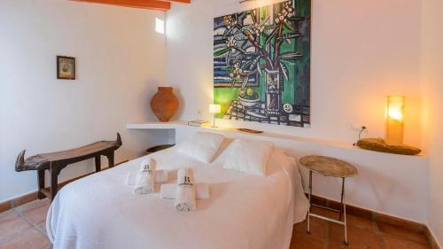 una camera da letto con un letto bianco e un quadro sul muro di The Hunting Lodge Alcaucín by Ruralidays ad Alcaucín