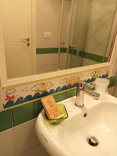 a bathroom sink with a mirror and a book on it at Borgo 800 in San Nicola Arcella