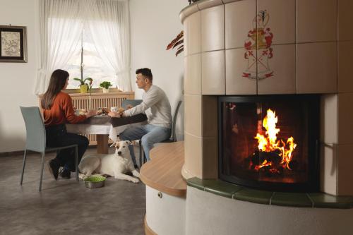 a man and woman sitting at a table in front of a fireplace at Hotel Castel Mani in San Lorenzo in Banale