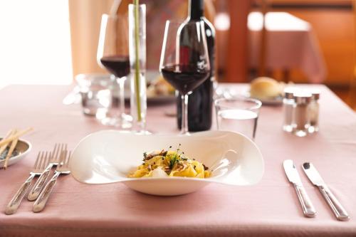 a plate of food on a table with wine glasses at Hotel Castel Mani in San Lorenzo in Banale