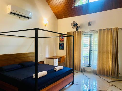 Schlafzimmer mit einem Bett und einem Schreibtisch mit einem Ventilator in der Unterkunft 1000 SILVERS -Farmhouse Stay in Mysore