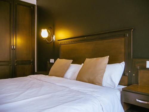 a bedroom with a large white bed with a wooden headboard at Hotel L'Aéroport in Nador