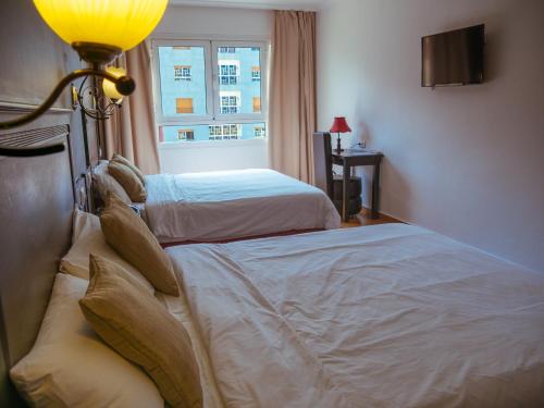 two beds in a hotel room with a window at Hotel L'Aéroport in Nador