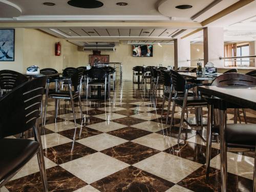 un restaurante con sillas negras y suelo a cuadros en Hotel L'Aéroport, en Nador