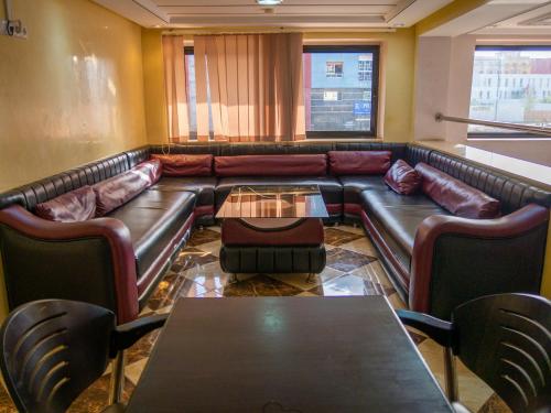 a living room with a leather couch and a table at Hotel L'Aéroport in Nador