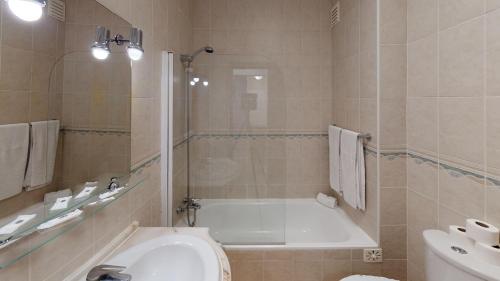 a bathroom with a tub and a toilet and a sink at Praia da Lota Beachfront Resort - Hotel & Apartments in Manta Rota