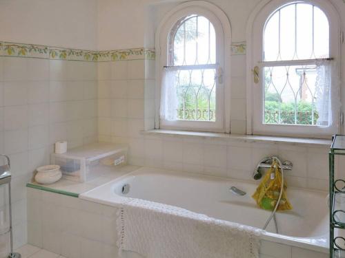 - une salle de bains blanche avec baignoire et 2 fenêtres dans l'établissement Villa Solaria, à Alexandrie