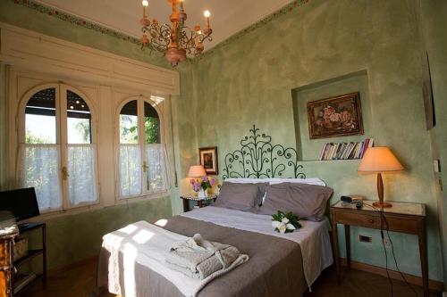 a bedroom with a bed and two windows and a chandelier at Villa Solaria in Alessandria