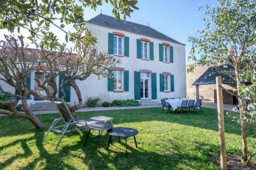 a house with a chair and a table in the yard at Demeure familiale de Préfailles pour 12 personnes in Préfailles