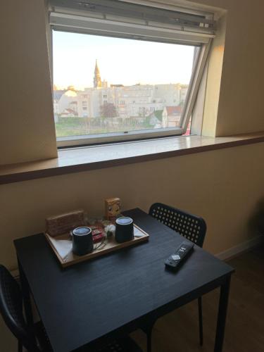 une table avec deux tasses sur un plateau devant une fenêtre dans l'établissement Reims Porte de Paris, à Reims