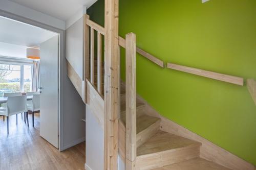 a staircase in a room with a green wall at Courlis Cendré in Courseulles-sur-Mer