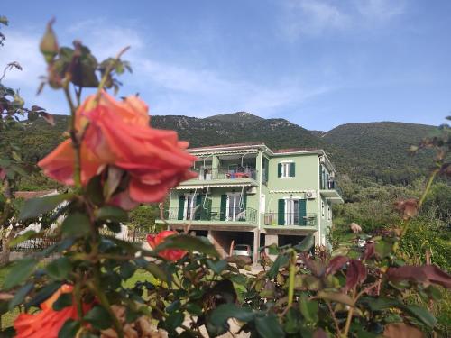 a green house with a red rose in front of it at Rosegarden in Sami