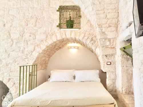 uma cama num quarto com uma parede de pedra em Il Piccolo Frantoio em Ostuni