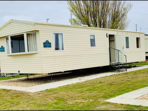 a small white house with a staircase in a yard at Trusville Mablethorpe 3 Bedroom Caravan . Beachside site ! in Mablethorpe