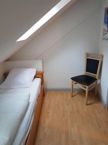 une chambre avec un lit et une chaise dedans dans l'établissement Le petit montagnard, à Cauterets