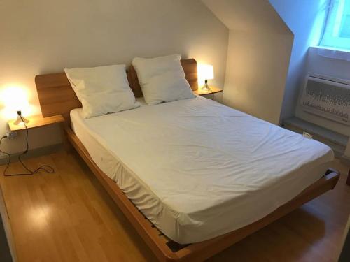 un lit avec des draps blancs et des oreillers dans une chambre dans l'établissement Le petit montagnard, à Cauterets