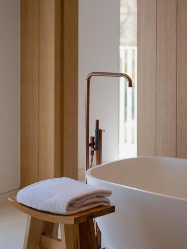 a bathroom with a tub and a stool with a towel at The Standard, Ibiza in Ibiza Town