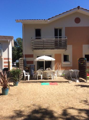 a house with a table and chairs and an umbrella at Résidence domaine des sables ROUTE 66 in Soulac-sur-Mer
