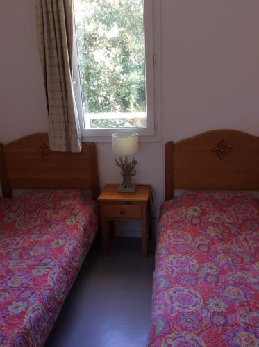 a bedroom with two beds and a window and a table at Résidence domaine des sables ROUTE 66 in Soulac-sur-Mer