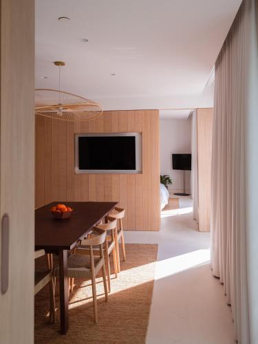 a dining room with a table and chairs and a television at The Standard, Ibiza in Ibiza Town