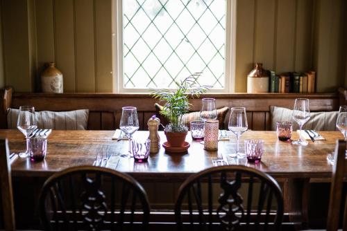 a wooden table with glasses and a potted plant on it at Beaulieu Hotel in Lyndhurst