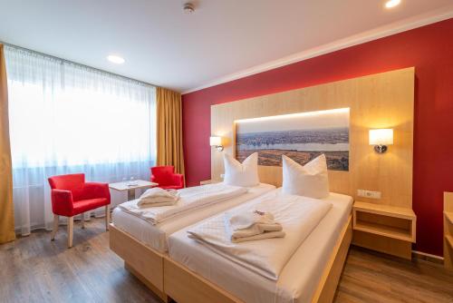 a hotel room with a bed and a red wall at Das Hotel an der Stadthalle - Rostock Hbf in Rostock
