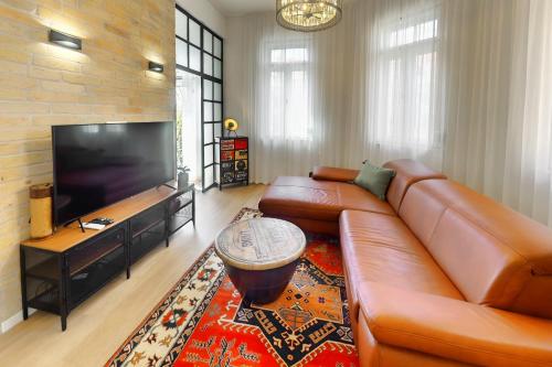 a living room with a leather couch and a flat screen tv at Synagoge view loft Bestern in Szeged