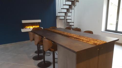 a room with a bar with chairs and a fireplace at Appartement moderne et spacieux in Sedan