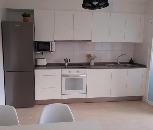a kitchen with white cabinets and a stainless steel refrigerator at Apto. en zona tranquila próximo a Santiago de C. in Brion