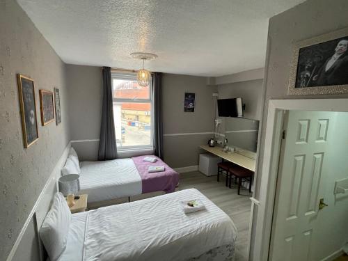 a room with two beds and a desk and a window at Topaz Blackpool in Blackpool