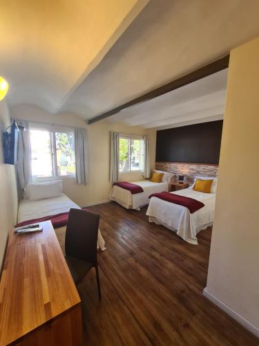 a hotel room with two beds and a table at Nova Posada in Colonia del Sacramento