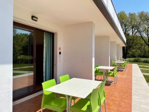 a row of tables and green chairs on a patio at Bran & Denise Residence in Costermano sul Garda