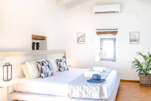ein weißes Schlafzimmer mit einem Bett mit blauem Hut darauf in der Unterkunft Green Dia's Mansion in Arménoi