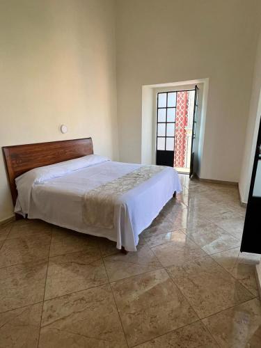 a bedroom with a bed and a large window at Hotel Catedral in Cuernavaca