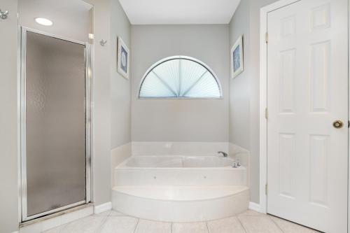 a white bathroom with a tub and a shower at Reduced Rates - Waterfront Heated Pool Home with dock, grill, near Fisherman's Village in Punta Gorda
