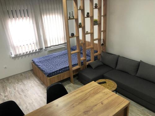 uma sala de estar com um sofá, uma cama e uma mesa em Apartman Lena em Prijedor
