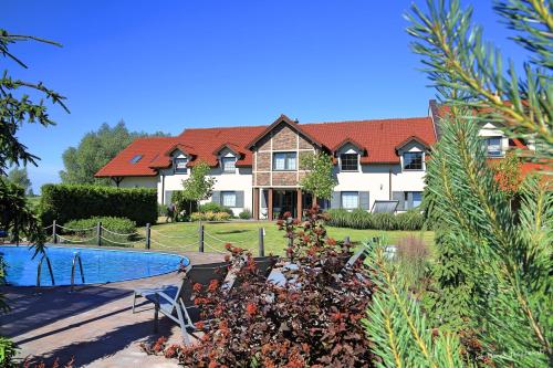 a house with a swimming pool in front of it at Tulipanowy Gościniec in Jantar
