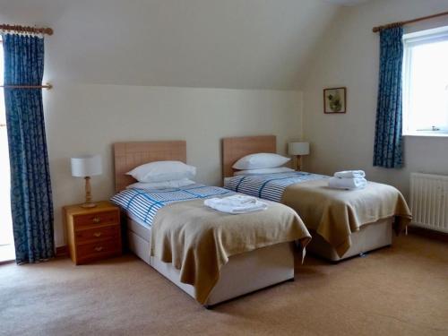 Tornacraig 8 Person Country House on Royal Deeside في أبوين: غرفة نوم بسريرين ونافذة