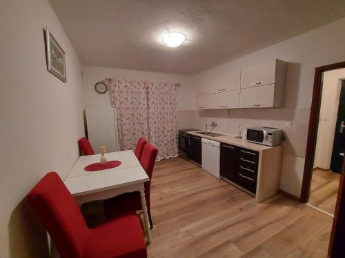 uma cozinha com uma mesa e cadeiras vermelhas num quarto em Country House Iva em Trbounje