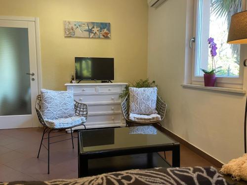 a living room with two chairs and a tv at Grand Pool Apartment Ika-Opatija in Opatija