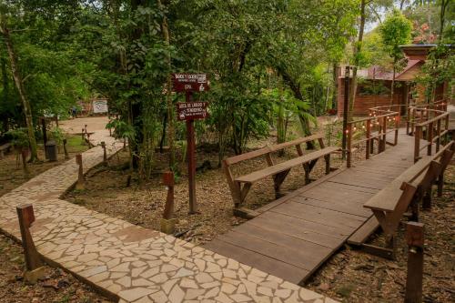 a wooden boardwalk in a park with benches and signs at Cabañas Kin Balam Palenque in Palenque