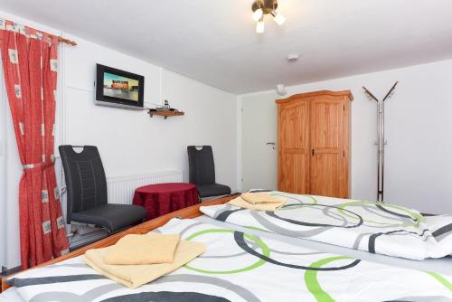 a bedroom with a large bed and two chairs at Pension Pradler Zimmer Erdgeschoß in Carolinensiel