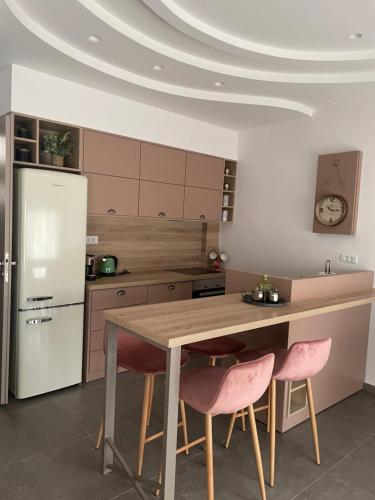 Una cocina con una mesa y dos sillas rosas. en Big blue suites gf, en Ierápetra
