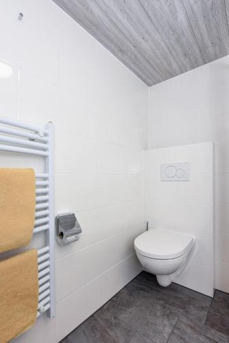a white bathroom with a toilet in a room at Pension Pradler Zimmer Erdgeschoß in Carolinensiel