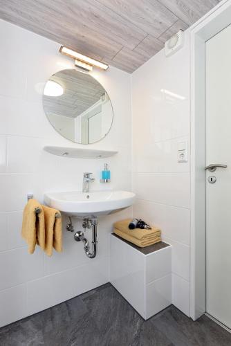 a white bathroom with a sink and a mirror at Pension Pradler Zimmer Erdgeschoß in Carolinensiel