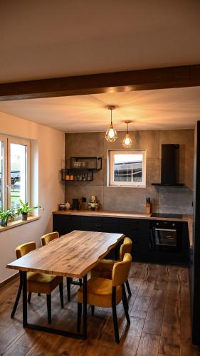 a kitchen with a wooden table and some chairs at Ośrodek Wypoczynkowo Sportowy Pod Żurawiem Apt. 2 in Karolewo